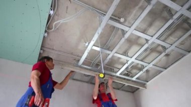 Tornavida ve bant ölçüsü set tavan profili ile iki işçi