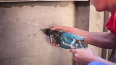 Worker drills openings in wall for mounting of steel brackets