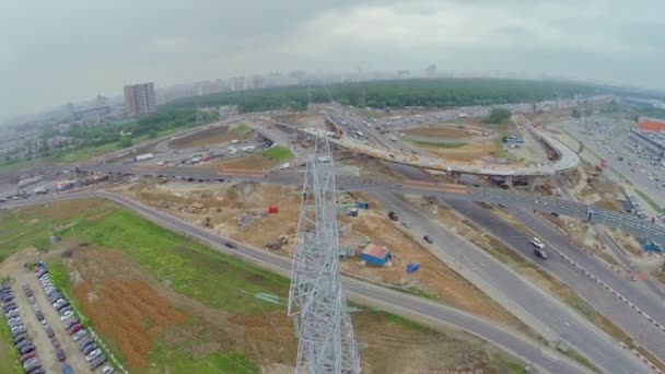 Linha de energia contra a paisagem urbana com canteiro de obras e tráfego — Vídeo de Stock