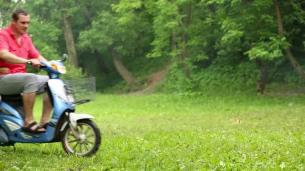 Uomo su scooter con rimorchio si ferma a prato erboso verde . — Video Stock