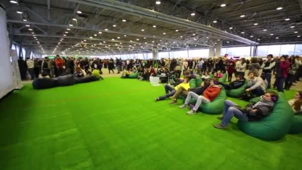 People sit on soft chairs near screen at Geek Picnic. — Stock Video