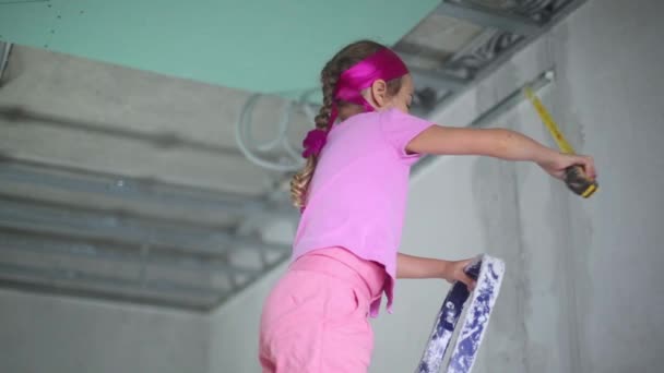 Klein meisje staat op ladder met Ape regel in gerepareerde appartement — Stockvideo