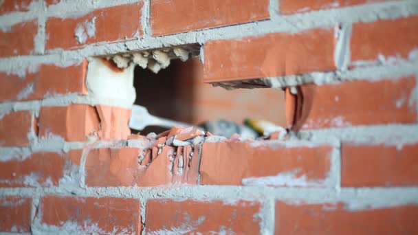 Manos en el hombre sosteniendo perforador y haciendo agujero en la pared de ladrillo — Vídeo de stock