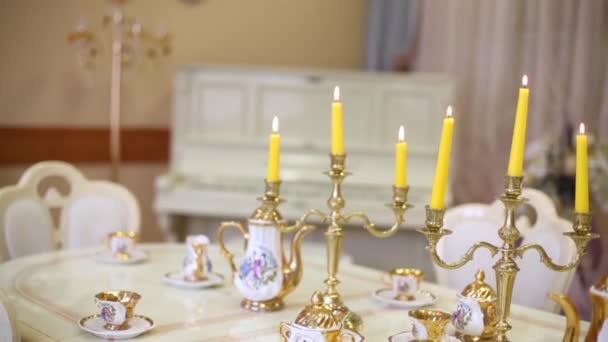 Table with set of porcelain dishes and lighted candles — Stock Video