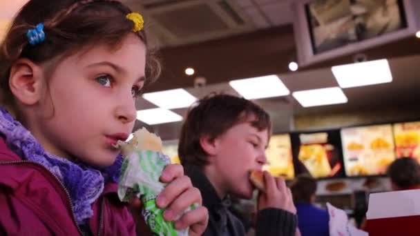 Junge und Mädchen essen Imbiss im Restaurant kfc in Moskau. — Stockvideo