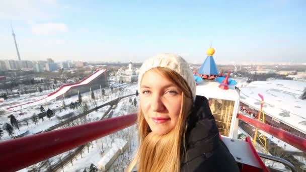Young pretty woman smiles and looks at sun on ferris wheel — 비디오