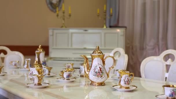 Mesa com conjunto de pratos de porcelana em sala de luz vazia com piano — Vídeo de Stock