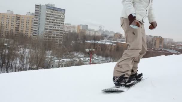 Snowboarder saltando por la colina y desciende lentamente — Vídeos de Stock
