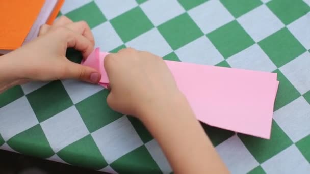 Hands of child making colored paper airplanes at table — Stock Video