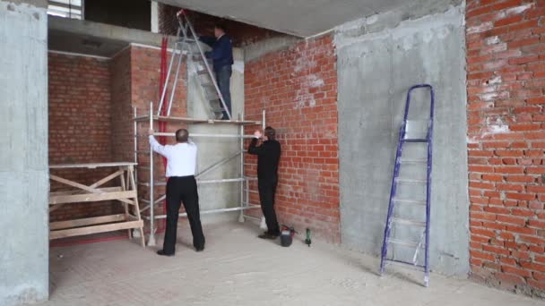 Three men on stepladder and scaffolding in apartment in building — Stock Video