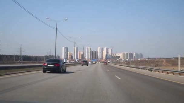 Многие машины быстро едут по шоссе в большой город в летний день — стоковое видео