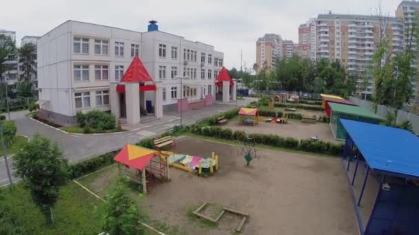 Детский сад с детской площадкой рядом с жилыми домами — стоковое видео