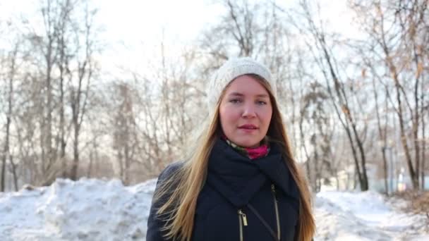 Красивая женщина в белой шляпе гуляет в парке в зимний день — стоковое видео