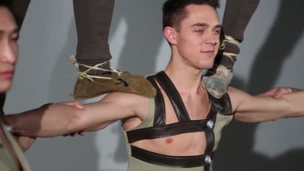 Visages de quatre jeunes hommes en costumes faisant tour acrobatique — Video