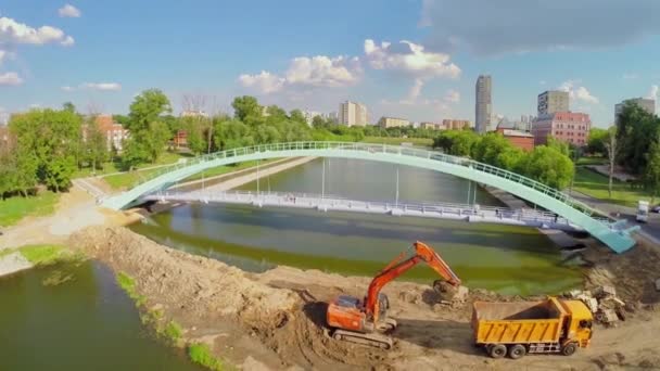 Bagator načítá náklaďák na písečných hromadách blízko mostu nad rybníkem — Stock video