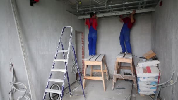 Dva muži v uniformě nainstalovat rámce pro zavěšené strop v novém bytě — Stock video