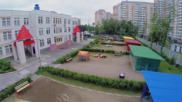 Дети играют на детской площадке в пасмурный весенний день — стоковое видео