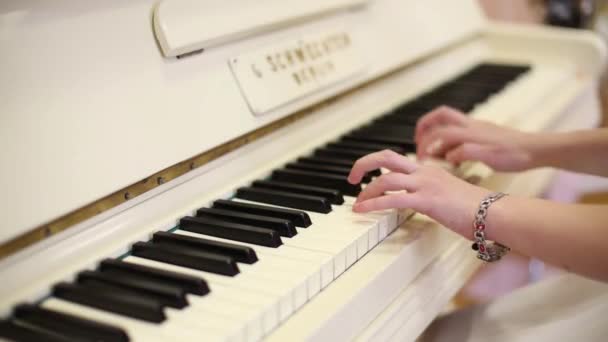 Beautiful hands of girl in bracelet playing white piano — Stock Video