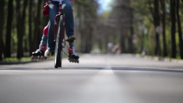 Cyklista s cestujícím v letním parku. Mělká hloubka ostrosti — Stock video