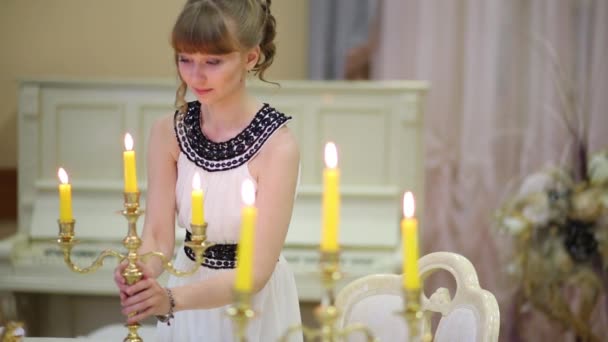 Mädchen trägt Kerzenständer, setzt ihn auf das Klavier und setzt sich zum Spielen — Stockvideo