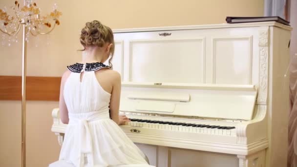 Costas da menina em vestido branco tocando piano na sala de luz — Vídeo de Stock