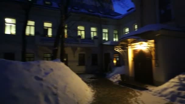 Kvällen innergård med mörka nakna trädstammar i snödrivor. — Stockvideo