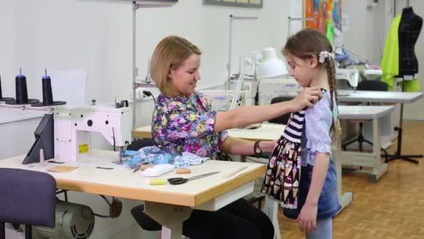 Sastre hembra se sienta en la mesa y se aplica vestido a la niña — Vídeos de Stock