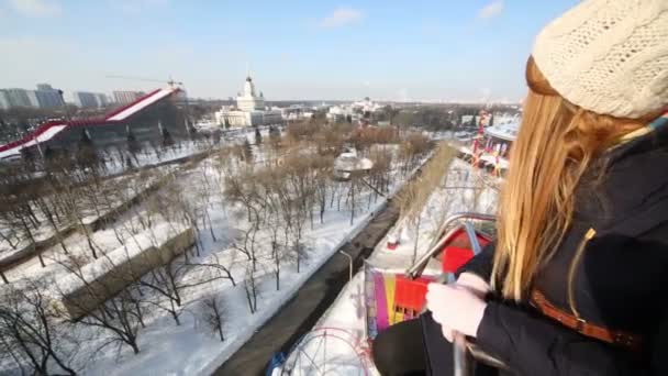 Mujer joven mira hacia abajo en la rueda del ferris en el día de invierno — Vídeo de stock