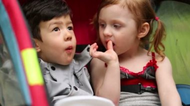 Küçük erkek ve kız patates cipsi, karavanda oturup yemek.