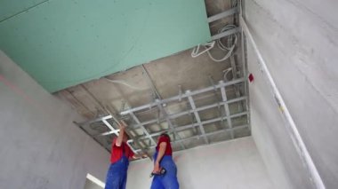 Workers verify accuracy of installation frame for hung ceiling