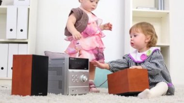 İki küçük kız evde odada halı üzerinde stereo sistemi oynamak