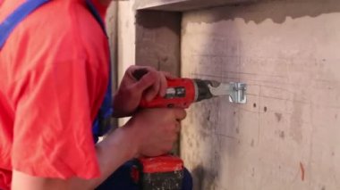 İşçi çelik braketi duvara elektrik vida silahla giderir.