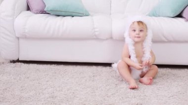 Beyaz yumuşak pantolon ve şapka yalınayak küçük çocuk halı oturur