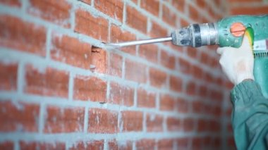 Erkek elleri tutan perforatör kırmızı tuğla duvar kırma