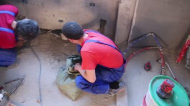 Alt kat seviyesinde beton duvara yeni yapılmış karık temizler.