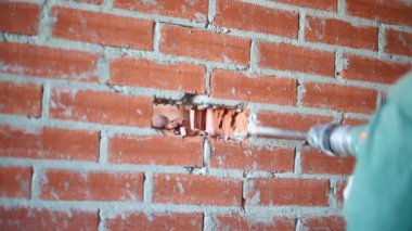 Tuğla duvarda delik açma perforatör tutan adam eller
