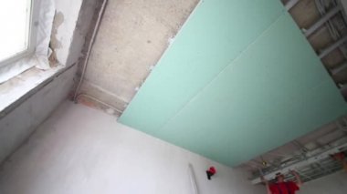 İki işçi yeni düz asılı tavan için çerçeve yüklemek