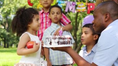 Küçük kız üçüncü doğum günü kutlamaları nda mum üfler