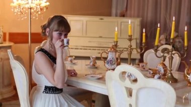 Güzel kız yanan mumlar ve içecekler çay ile masada oturur