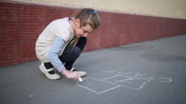 Küçük kız Caddesi üzerinde asfalt üzerinde seksek çizmeye başlar