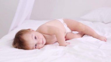 Şirin Bebek bezi içinde beyaz yatakta yatıyor ve uzak görünüyor