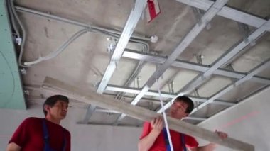 Workers verify accuracy of installation frame for hung ceiling