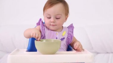 Küçük gülümseyen bebek sandalyesi oturur ve plaka üzerinde püresi yiyor