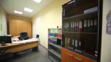 Geniş çalışma masası ve klasörlerle kitaplık ile küçük bir ofis