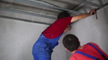 Üniformalı iki adam set tavan profili için ölçüm yapmak