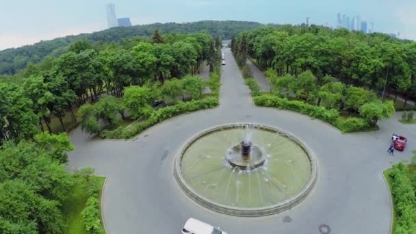 Paseos en coche alrededor de la fuente en el parque de la ciudad en el día de verano. Vista aérea — Vídeos de Stock