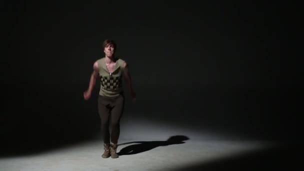 Przystojny, młody acrobat w średniowiecznym stroju skacze w ciemnym studio — Wideo stockowe