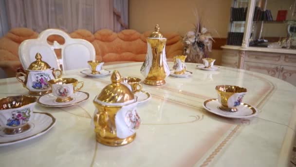 Table with set of beautiful porcelain dishes in empty light room — Stock Video