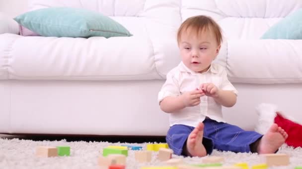 Mignon petit enfant se trouve près du canapé blanc parmi les jouets bricoleurs — Video