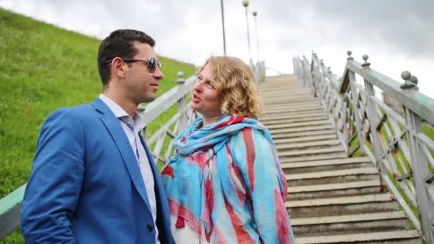 Вагітна жінка в білому і стильному чоловікові стоїть на сходах — стокове відео